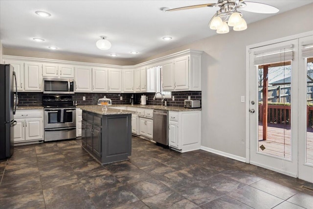 kitchen with decorative backsplash, white cabinets, baseboards, and appliances with stainless steel finishes