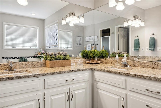 full bathroom with double vanity, a stall shower, and a sink