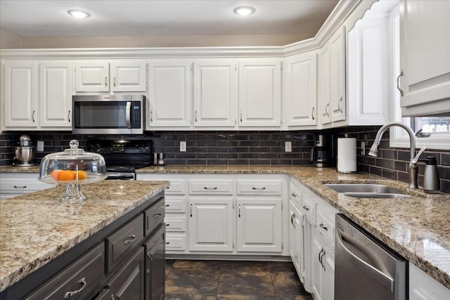 kitchen with decorative backsplash, white cabinets, appliances with stainless steel finishes, and a sink