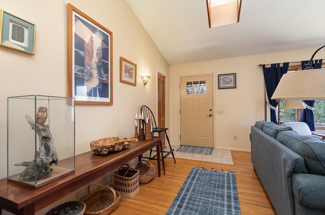 foyer entrance with vaulted ceiling, baseboards, and light wood finished floors