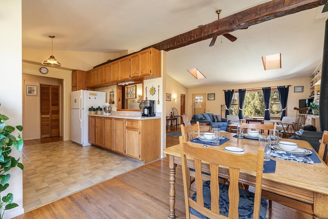 dining space with lofted ceiling with skylight, ceiling fan, and light wood finished floors