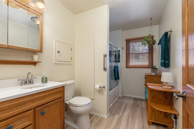 full bath featuring toilet, enclosed tub / shower combo, wood finished floors, baseboards, and vanity