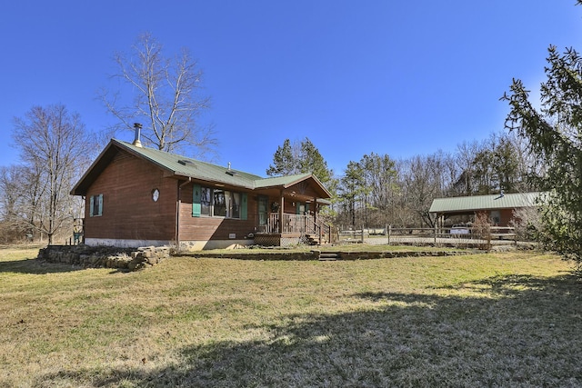 rear view of house with a yard, covered porch, and metal roof