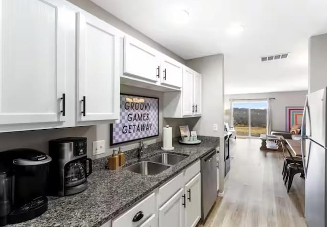 kitchen featuring a sink, stainless steel appliances, visible vents, and white cabinets