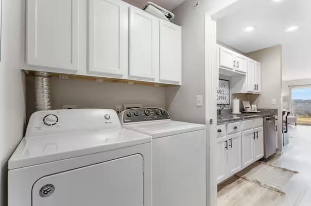 washroom with cabinet space, washing machine and dryer, and a sink