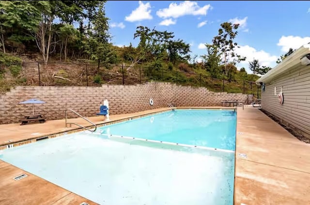 community pool with a patio area and fence