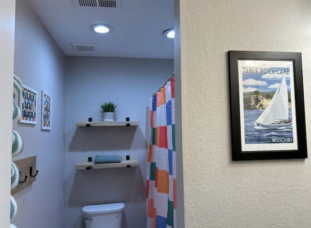 full bath with visible vents, toilet, a shower with curtain, and a textured wall