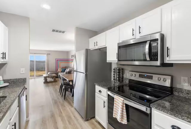 kitchen featuring white cabinetry, dark stone counters, visible vents, and appliances with stainless steel finishes