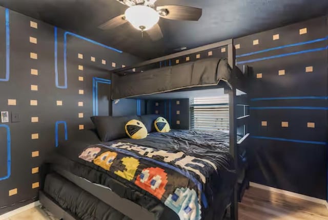 bedroom with ceiling fan, a garage, and wood finished floors