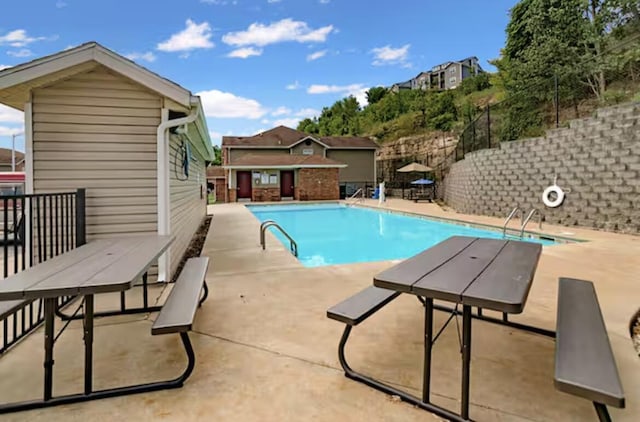 community pool featuring a patio, an outbuilding, and fence