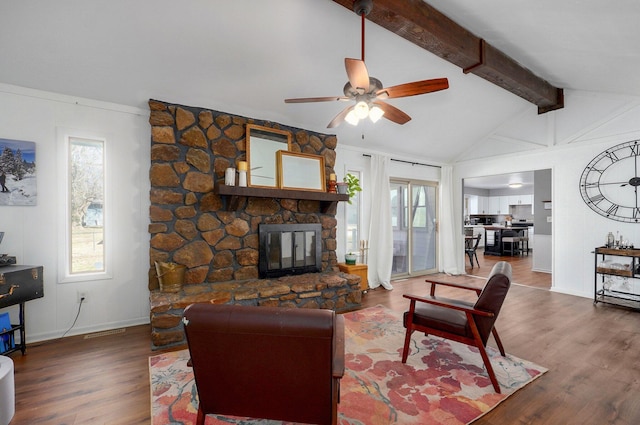 living room featuring a stone fireplace, plenty of natural light, lofted ceiling with beams, and wood finished floors