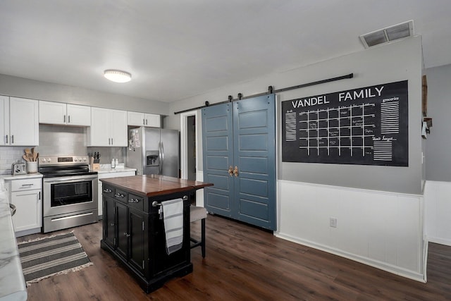 kitchen with visible vents, a barn door, wainscoting, appliances with stainless steel finishes, and dark wood-style floors