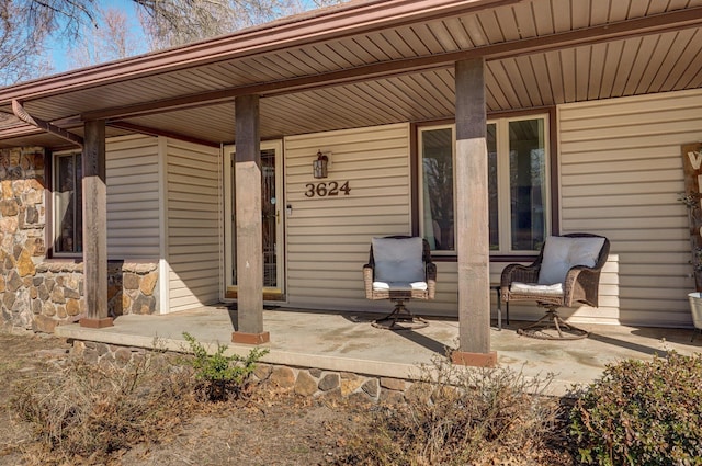 view of exterior entry featuring stone siding and covered porch