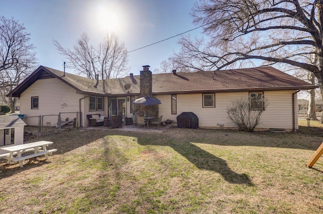 rear view of property featuring a gate, fence, a chimney, a patio area, and a lawn