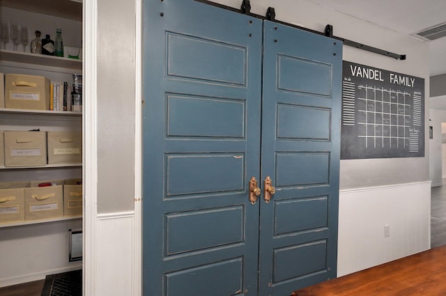 interior space with visible vents, a barn door, and wainscoting