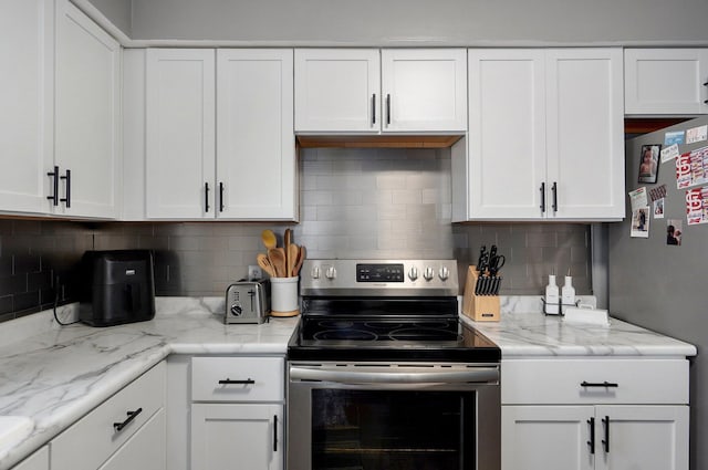 kitchen with decorative backsplash, appliances with stainless steel finishes, white cabinetry, and light stone countertops