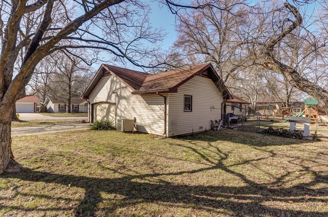 view of side of home with fence, a yard, a garage, crawl space, and central air condition unit