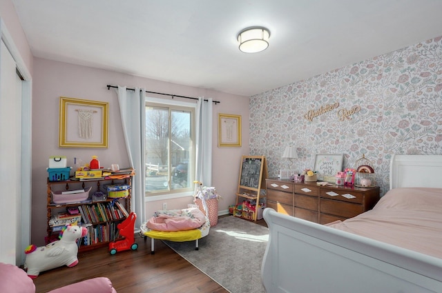 bedroom with a closet, baseboards, wood finished floors, and wallpapered walls