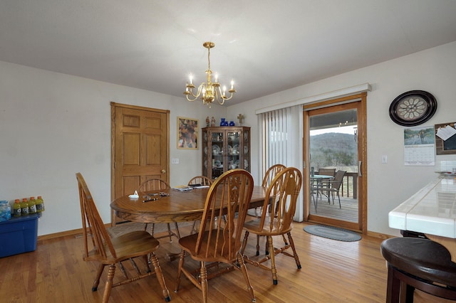 dining area featuring an inviting chandelier, baseboards, and light wood-style floors