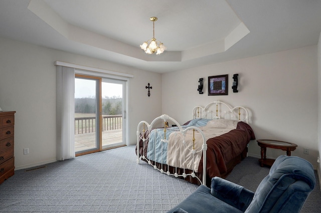 bedroom with visible vents, carpet floors, a tray ceiling, access to outside, and a chandelier