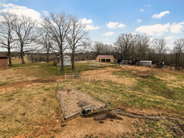 view of yard with a rural view, an outbuilding, and fence