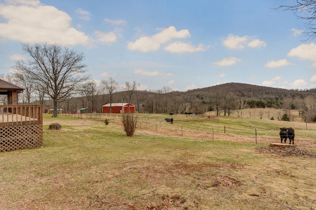 view of yard featuring a wooden deck, a rural view, and fence