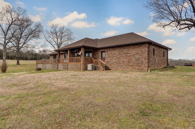 rear view of house with brick siding, central air condition unit, a lawn, and a shingled roof