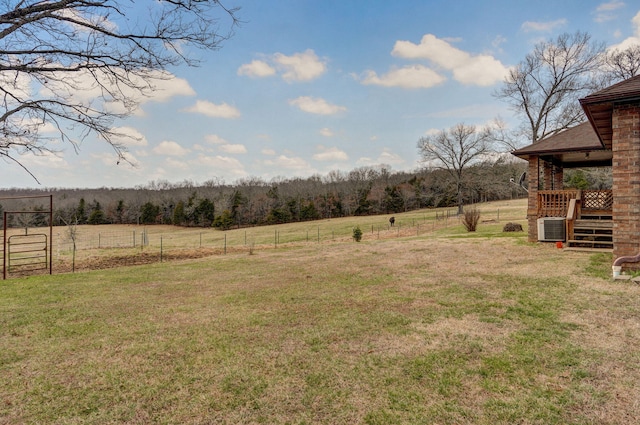 view of yard featuring a rural view, fence, and central AC