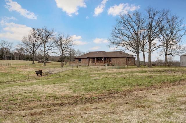 view of yard with an outdoor structure, a rural view, and fence