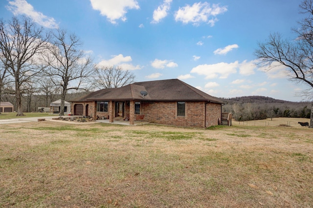 rear view of house featuring an attached garage, a lawn, and brick siding