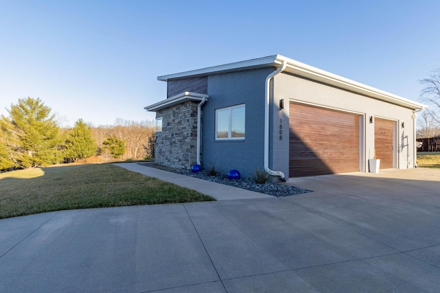 view of side of home with a yard, concrete driveway, a garage, stone siding, and brick siding