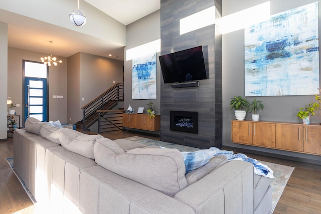 living area featuring a large fireplace, a notable chandelier, wood finished floors, and stairs