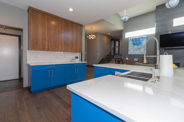 kitchen with tasteful backsplash, blue cabinetry, dark wood-type flooring, recessed lighting, and a sink