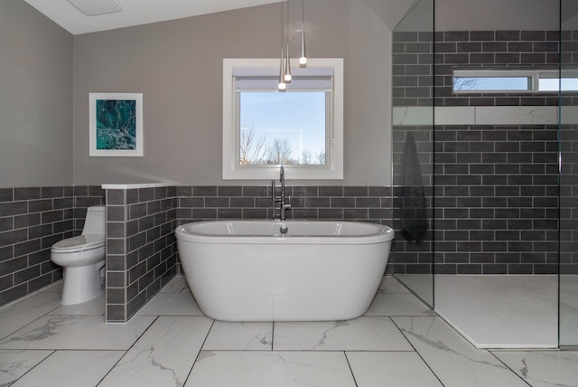 full bath with tile walls, a freestanding tub, marble finish floor, and walk in shower