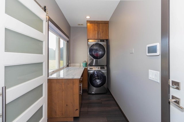 laundry room featuring dark wood finished floors, recessed lighting, cabinet space, and stacked washer and clothes dryer