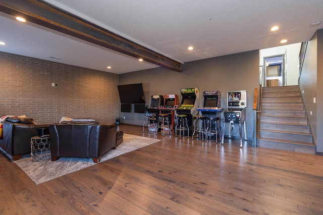 living room with beamed ceiling, hardwood / wood-style flooring, stairway, brick wall, and a dry bar