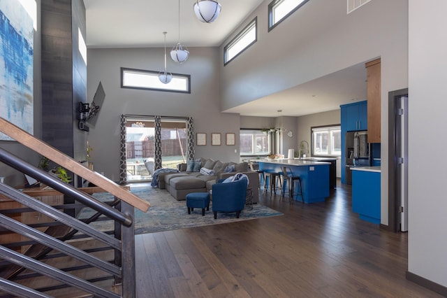 living room with dark wood finished floors, stairs, and a towering ceiling