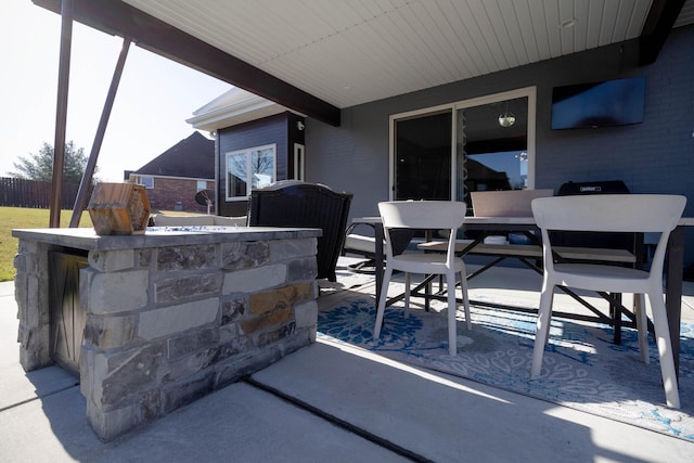 view of patio featuring outdoor dry bar, outdoor dining area, and fence