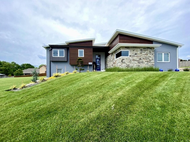 back of property with stone siding and a lawn