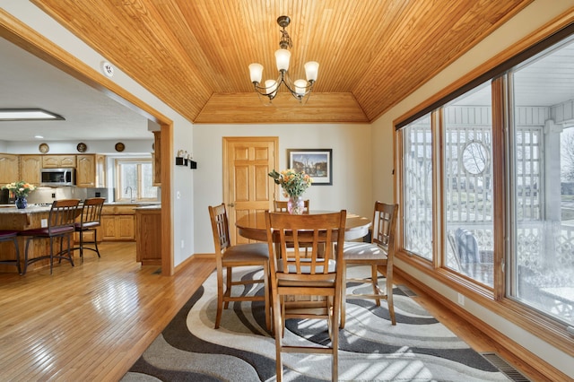 dining area featuring baseboards, visible vents, light wood-style flooring, wooden ceiling, and a raised ceiling