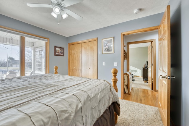 bedroom featuring ceiling fan, light wood-style floors, a closet, and a textured ceiling