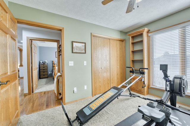 workout room featuring a wealth of natural light, baseboards, a textured ceiling, and a ceiling fan