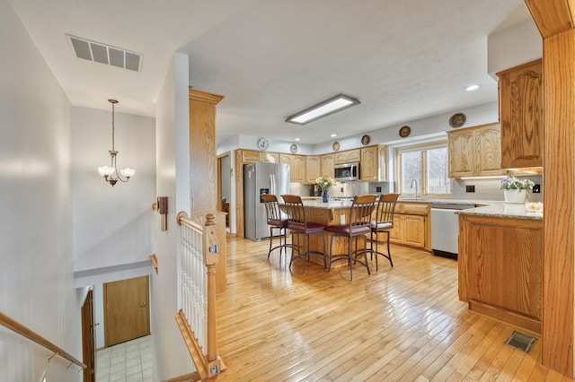 kitchen with visible vents, stainless steel appliances, a kitchen bar, and a sink