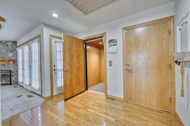 entrance foyer with visible vents, a fireplace, light wood-style floors, and baseboards