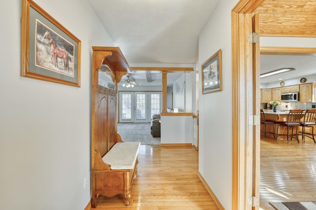 hall featuring french doors, baseboards, decorative columns, and light wood finished floors