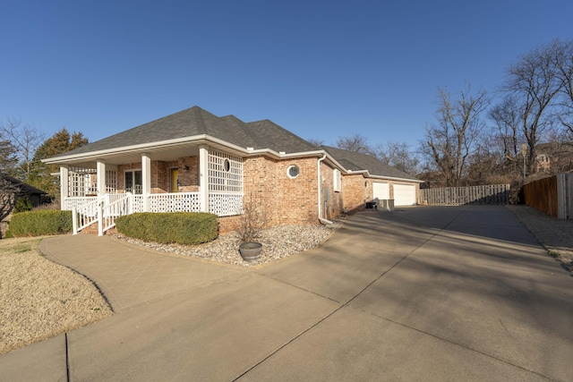 view of front of property with brick siding, fence, a porch, roof with shingles, and a garage