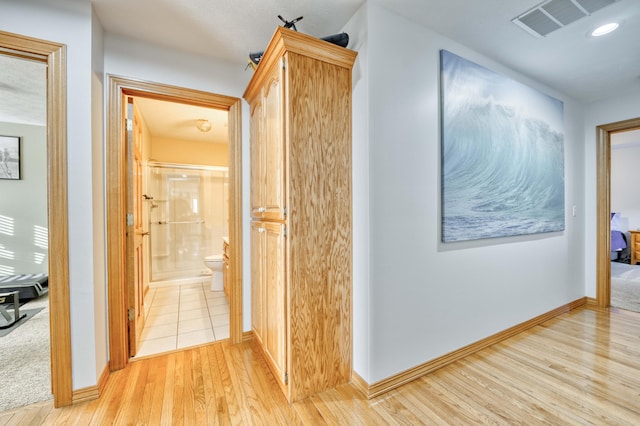 corridor featuring light wood-type flooring, visible vents, baseboards, and recessed lighting