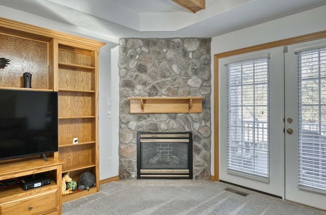 unfurnished living room featuring visible vents, a stone fireplace, carpet flooring, and french doors