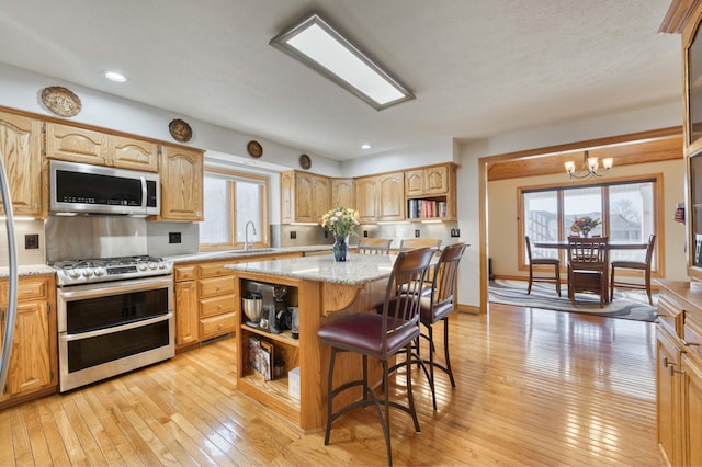 kitchen featuring open shelves, a center island, appliances with stainless steel finishes, and a sink