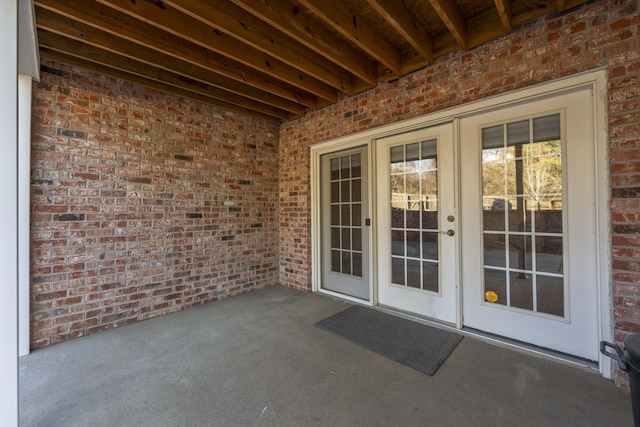 view of exterior entry featuring brick siding and french doors